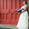 bride and groom pose in front of red door